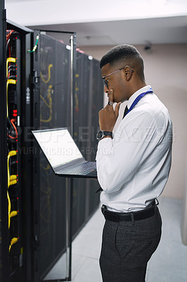 Buy stock photo Shot of a young male technician working in a server room