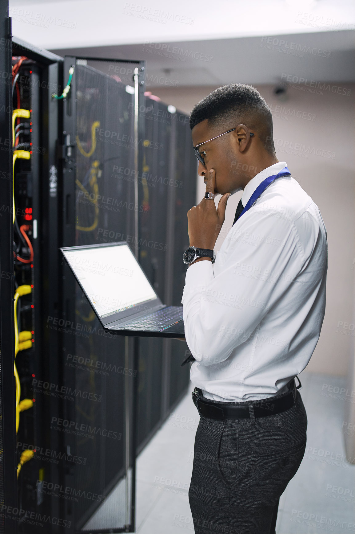 Buy stock photo Shot of a young male technician working in a server room