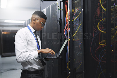 Buy stock photo Shot of a young male technician working in a server room
