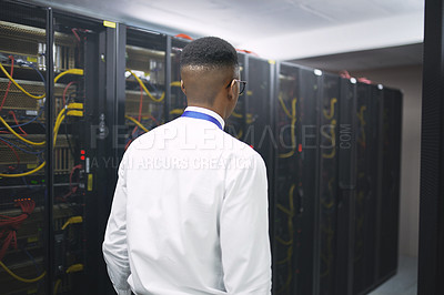 Buy stock photo Shot of a young male IT technician in a server room