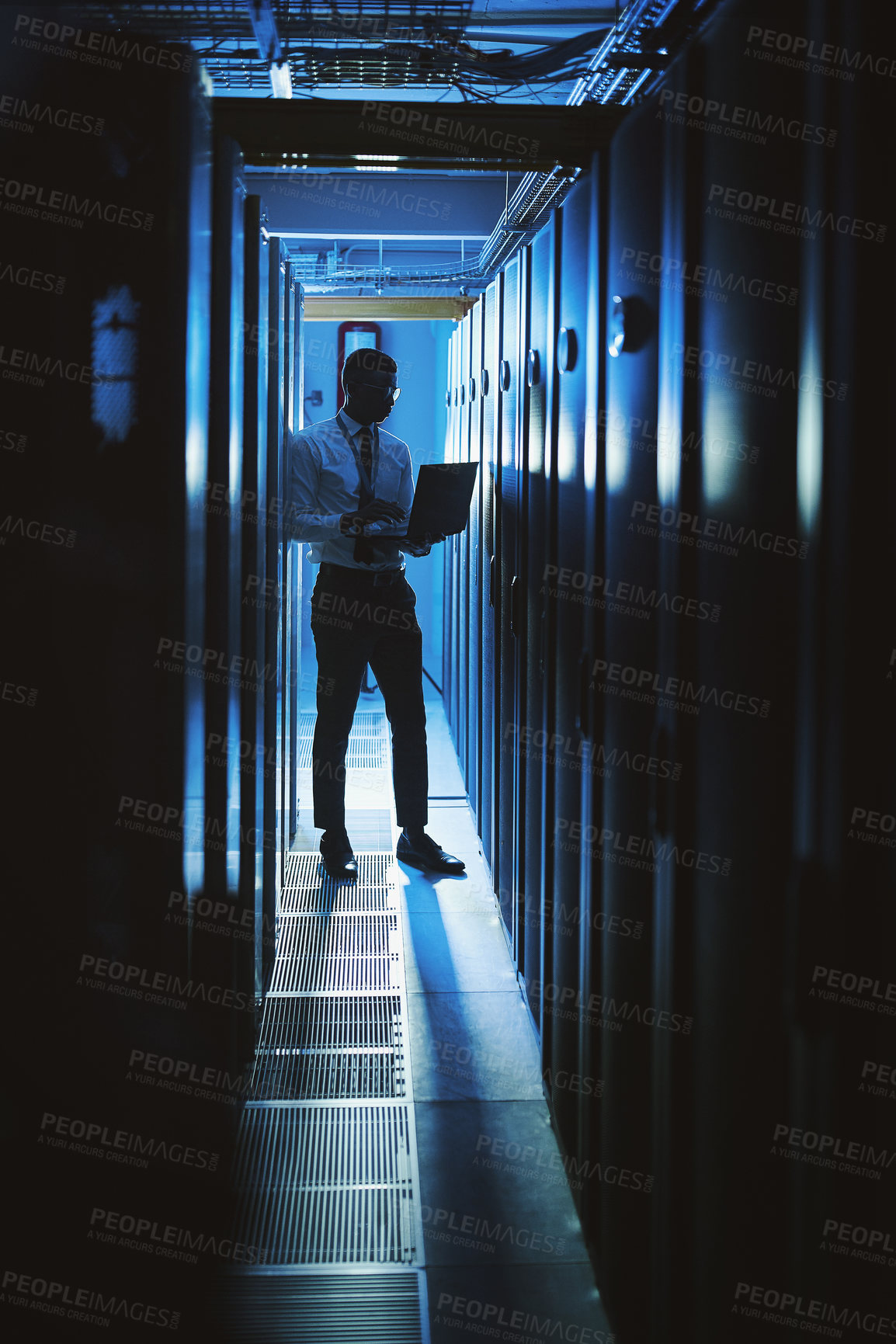 Buy stock photo Shot of a young man working in an IT server room