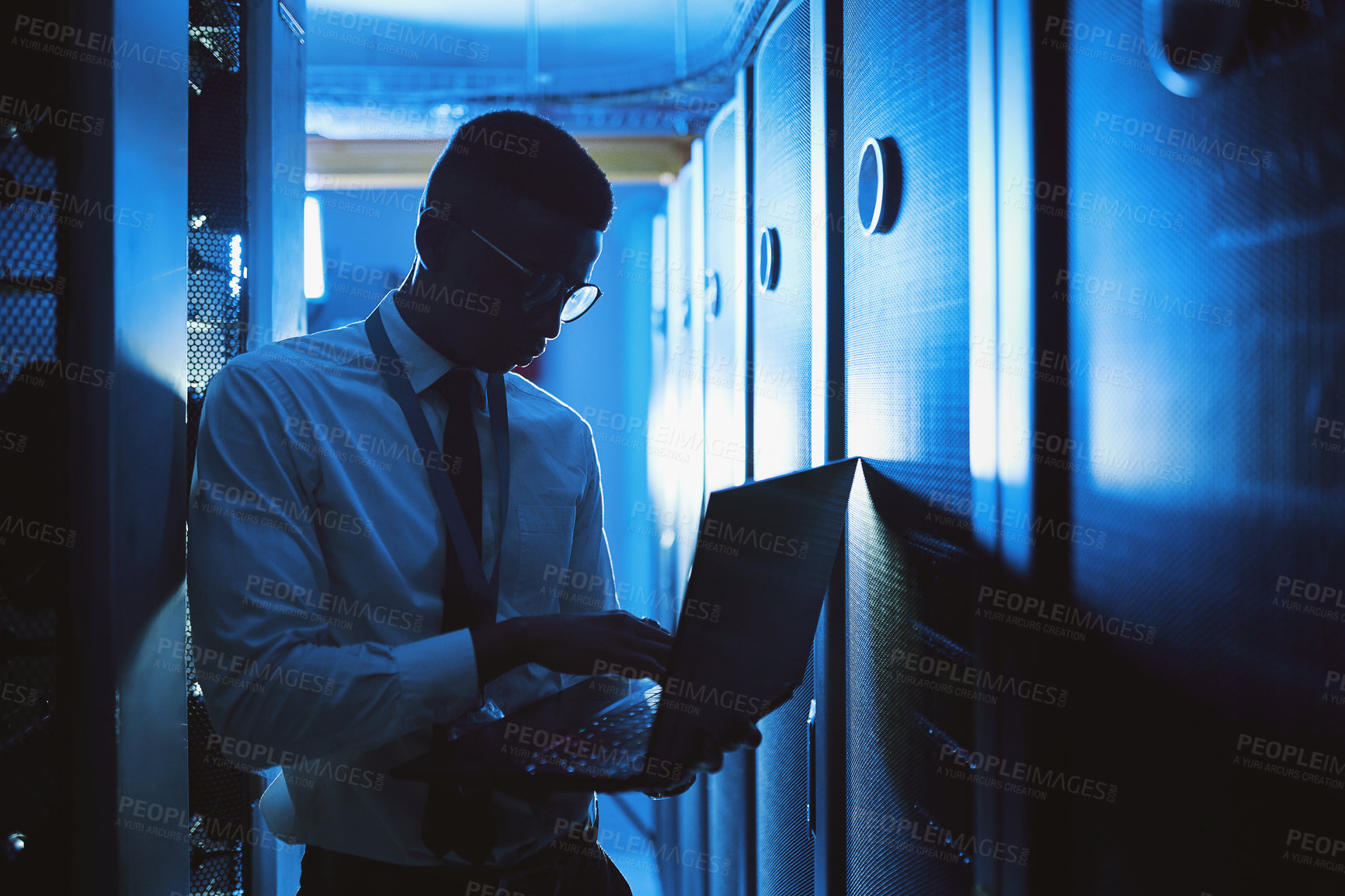 Buy stock photo Shot of a young man working in an IT server room