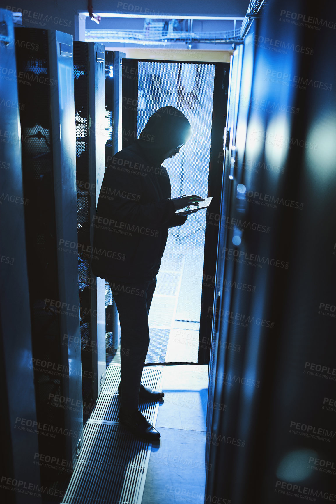 Buy stock photo Shot of a hacker using a digital tablet in a server room