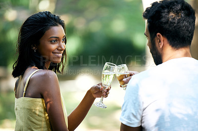 Buy stock photo Shot of a young couple making a toast while out on a date