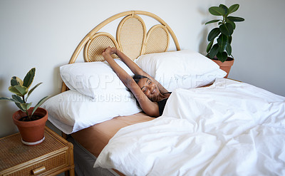 Buy stock photo Shot of a young woman stretching out her arms after waking up