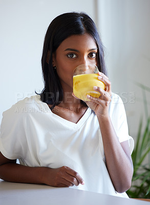 Buy stock photo Shot of a beautiful young woman drinking a glass of orange juice at home
