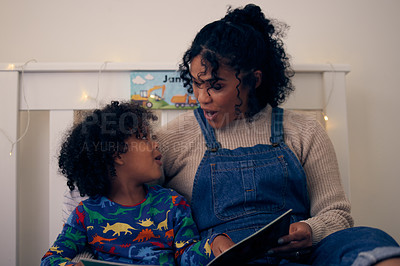 Buy stock photo Shot of a woman reading a book to her son at night