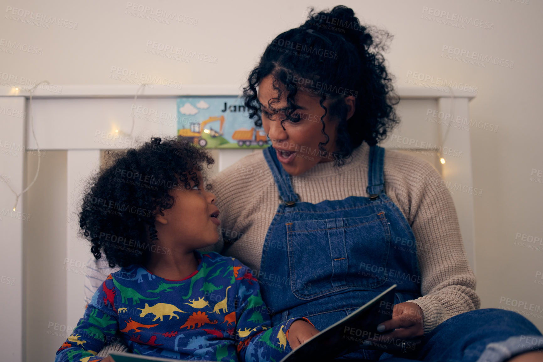 Buy stock photo Shot of a woman reading a book to her son at night