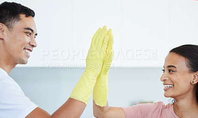 Buy stock photo Shot of a young couple high fiving each other while cleaning their kitchen