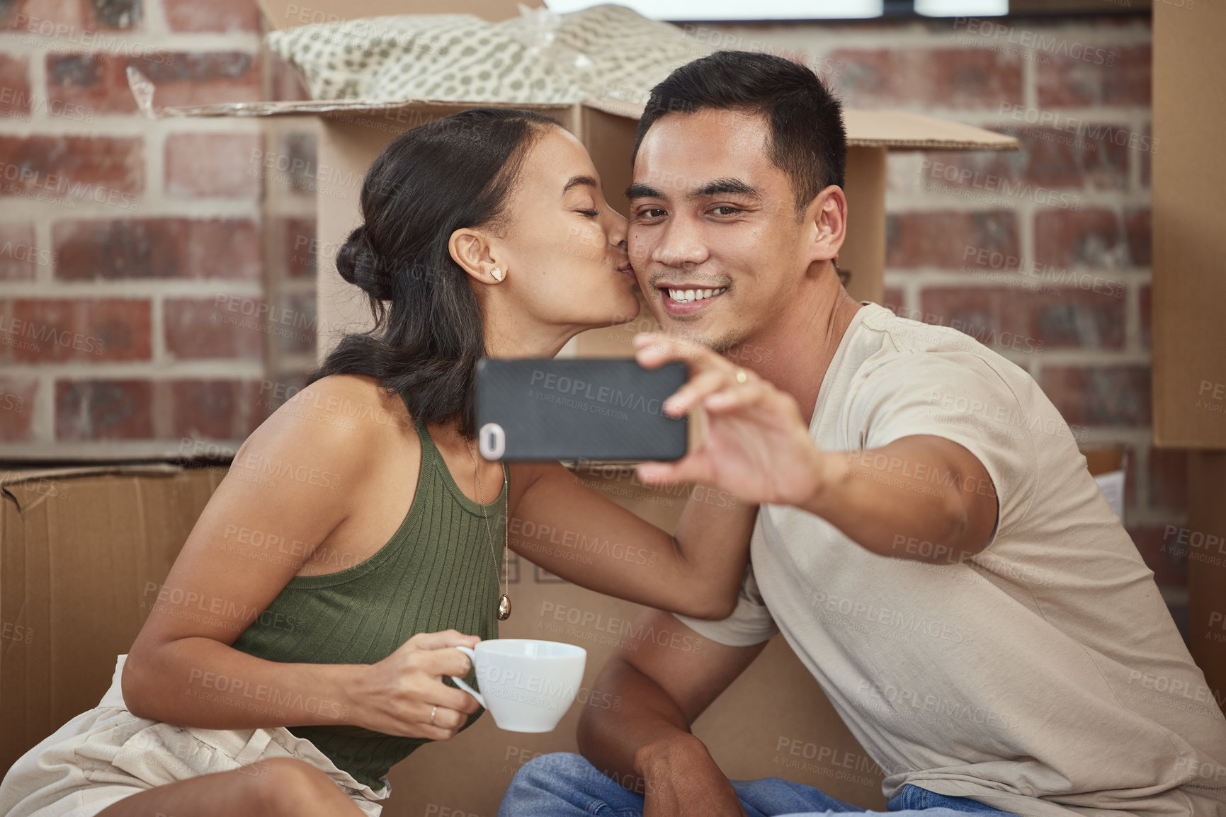 Buy stock photo Shot of a young couple taking a selfie while sitting in their new home