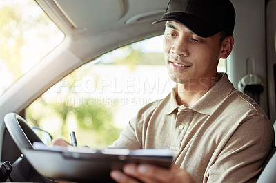Buy stock photo Shot of a delivery man checking the paperwork for his delivery in his car