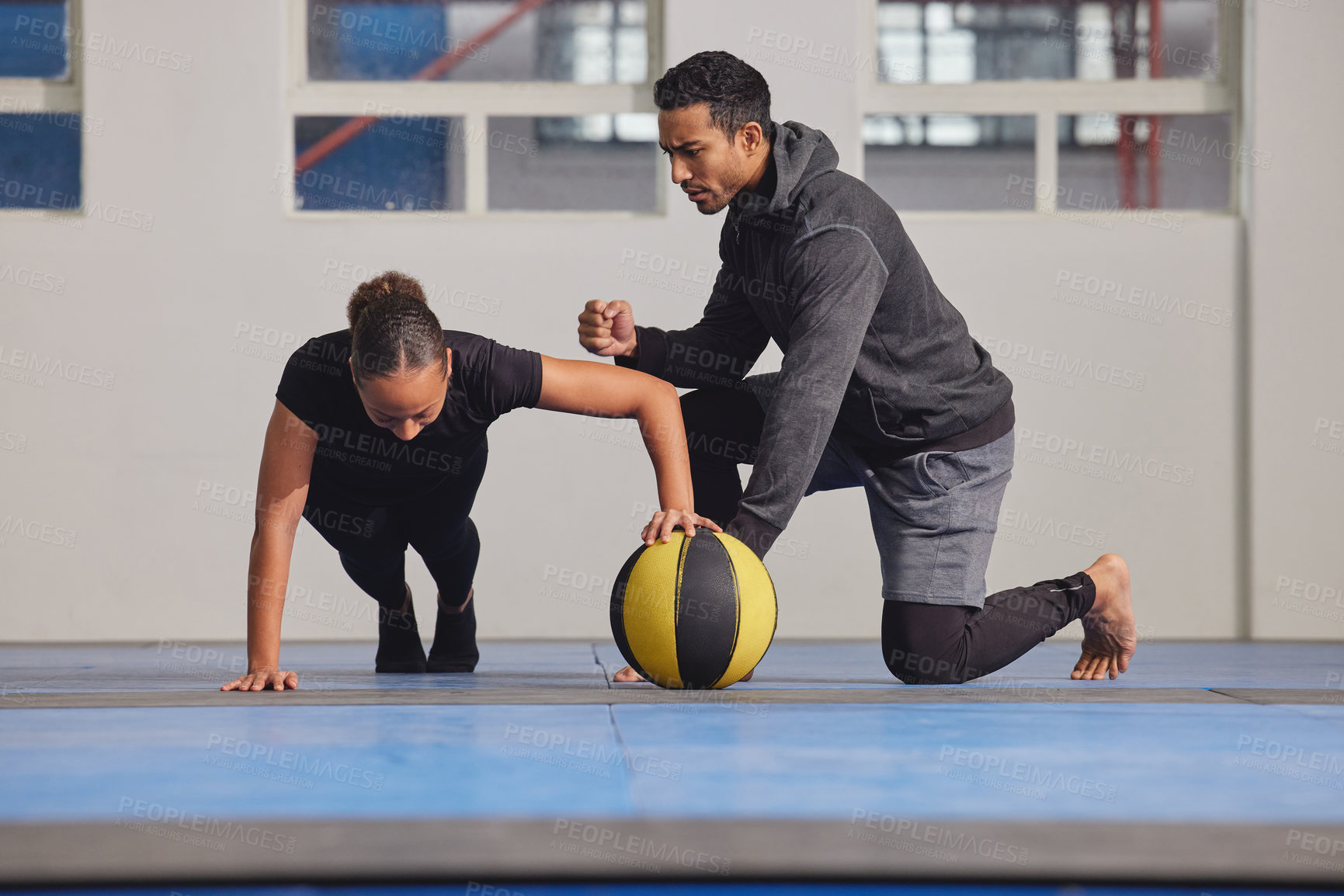 Buy stock photo Shot of a young woman exercising with a trainer at the gym