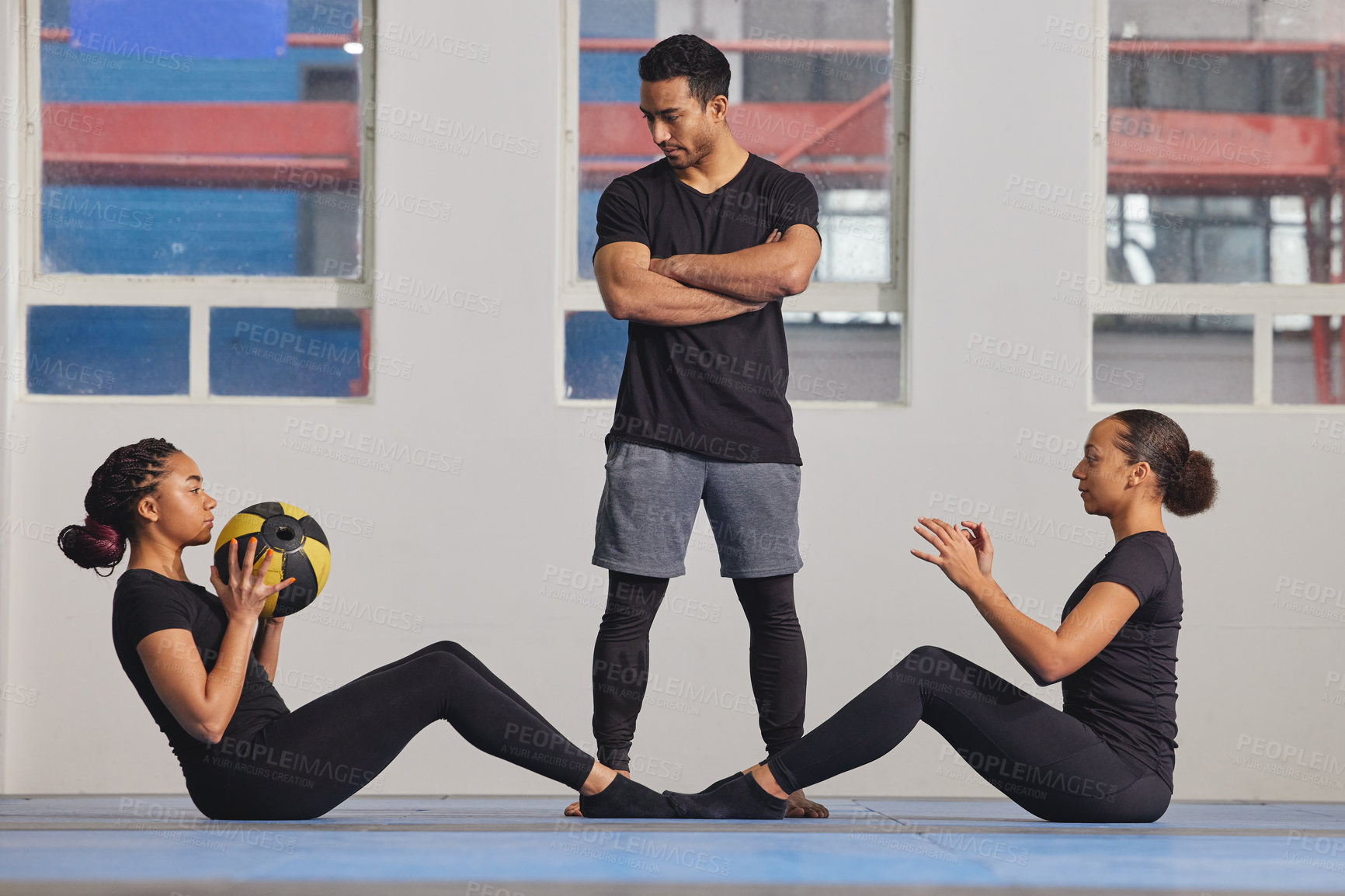 Buy stock photo Shot of two young women exercising with a trainer at the gym