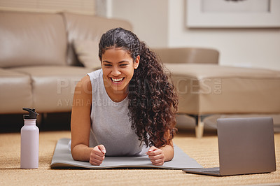 Buy stock photo Shot of an attractive young woman using her laptop to follow an online fitness class in her living room