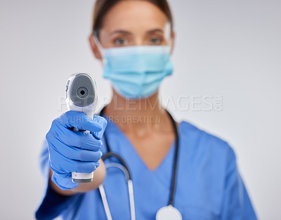 Buy stock photo Shot of a young female nurse holding a digital thermometer against a studio background