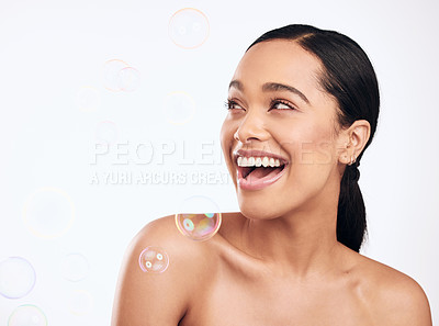 Buy stock photo Shot of bubbles floating over a beautiful woman in the studio