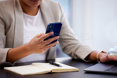 Buy stock photo Cropped shot of a young businesswoman using a cellphone while making notes at her desk in a modern office