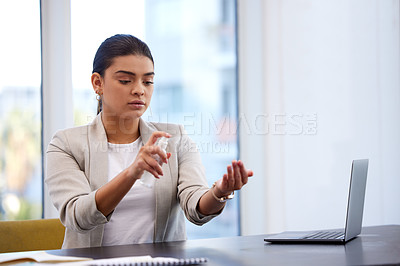 Buy stock photo Shot of a young businesswoman sanitising her work station in a modern office