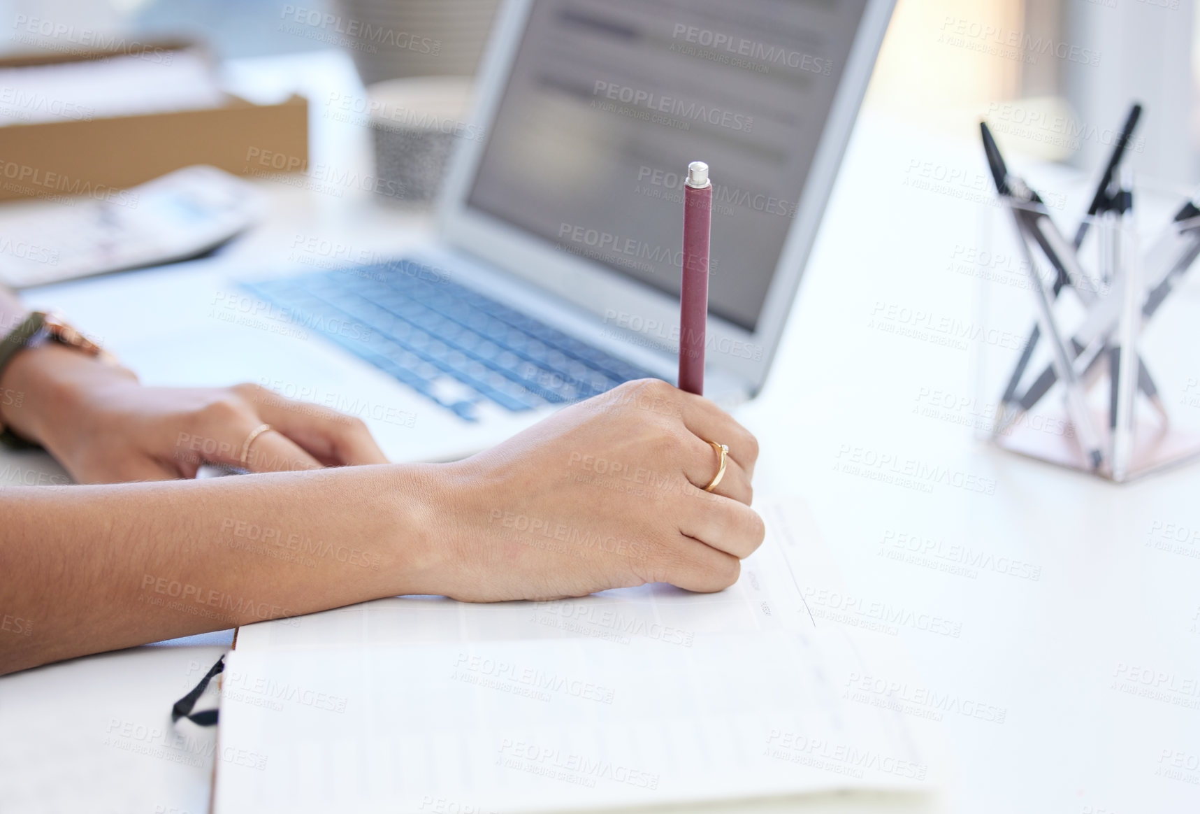 Buy stock photo Cropped shot of an unrecognizable businesswoman writing in her notebook while working at her desk in the office