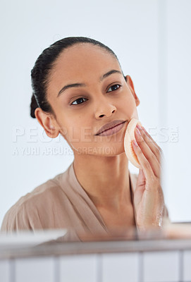 Buy stock photo Shot of an attractive young woman standing alone in her bathroom and home and cleansing her skin