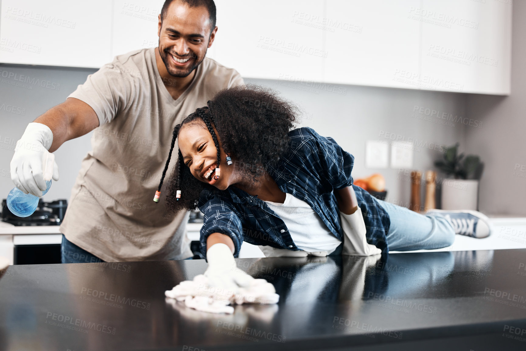 Buy stock photo Shot of a young girl helping her father clean the kitchen counter at home