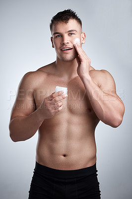 Buy stock photo Man, muscular torso and face cream in studio for skincare, dermatology or cosmetic for facial, morning routine or self care. Model, smile and portrait with lotion for aesthetic wellness or grooming  