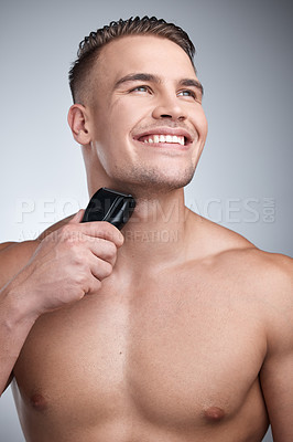 Buy stock photo Studio shot of an attractive young man shaving his face against a grey background