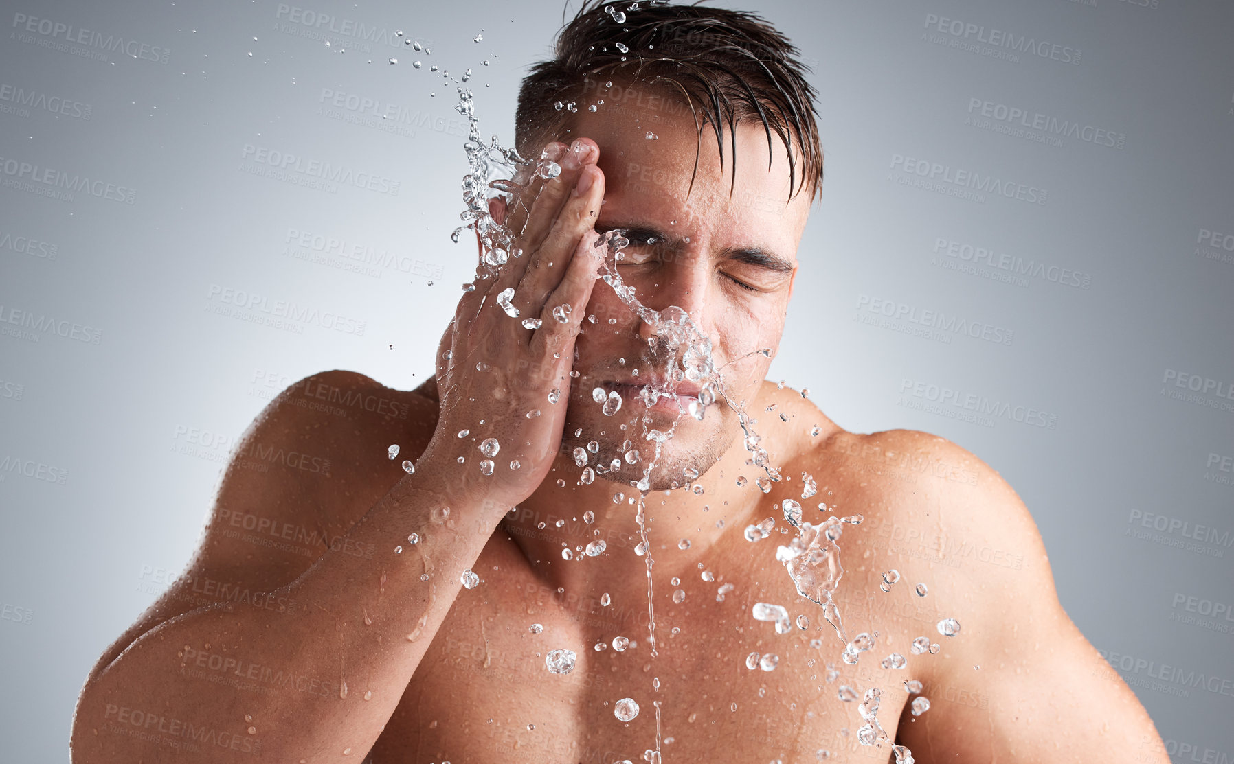 Buy stock photo Washing, studio and man with water, face and morning for splash of body, clean and routine for skincare. Hygiene, glow and person in grey background of bathroom, liquid and relax for bath of shine