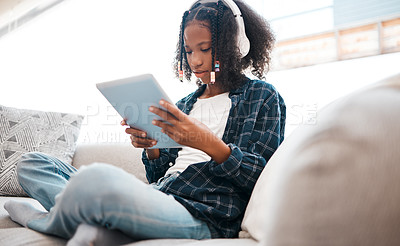 Buy stock photo Shot of a young girl relaxing while using a digital tablet at home