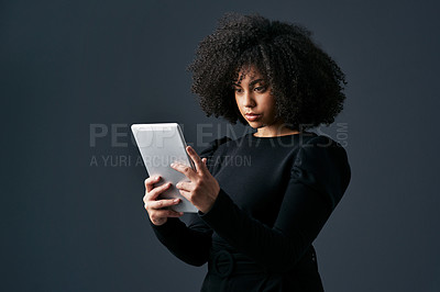 Buy stock photo Shot of a young businesswoman using a digital tablet against a studio background