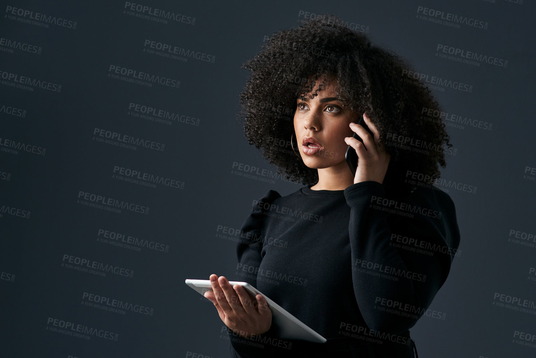 Buy stock photo Shot of a young businesswoman using her smartphone and digital tablet against a studio background