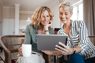 Buy stock photo Shot of two female friends drinking coffee while using a digital tablet