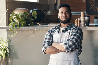 Buy stock photo Shot of a handsome young man standing outside his restaurant with his arms folded during the day