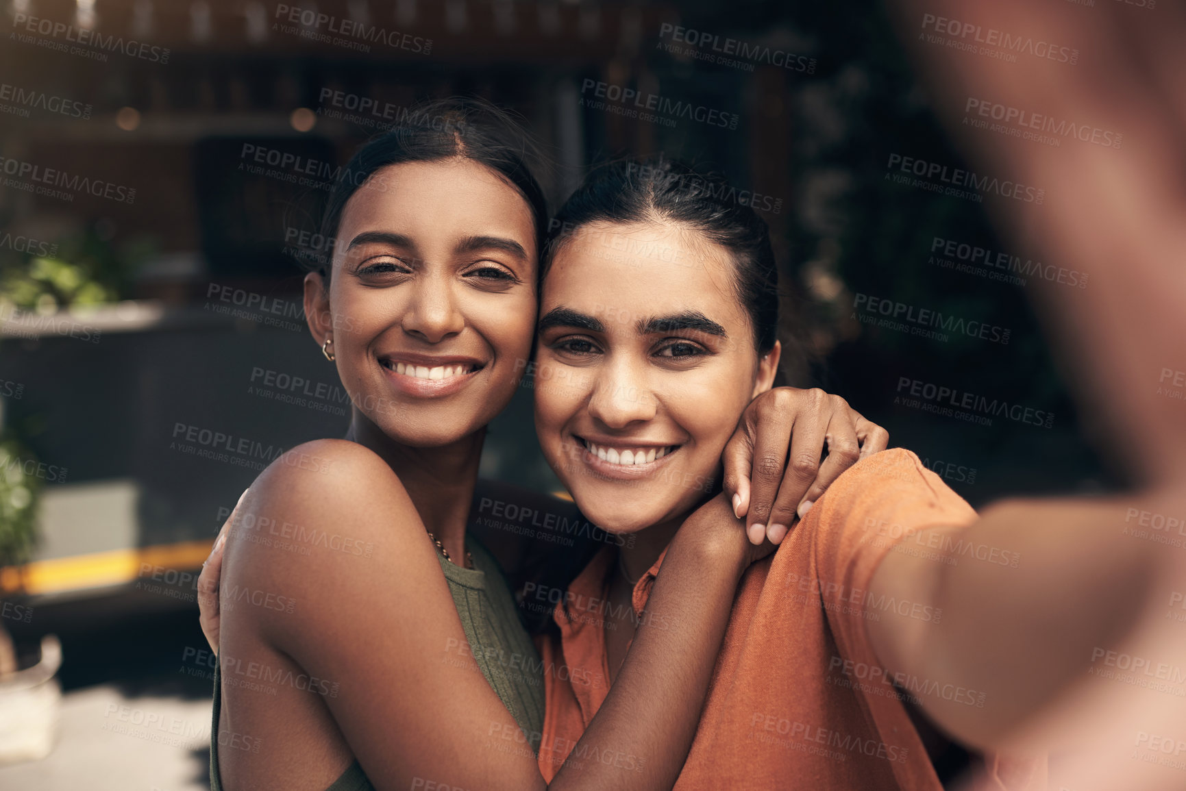 Buy stock photo Shot of two young friends standing outside a restaurant and taking selfies