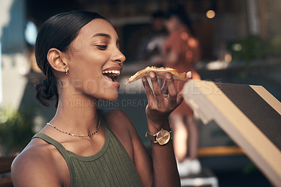 Buy stock photo Shot of an attractive young woman sitting and enjoying a freshly made pizza at a restaurant