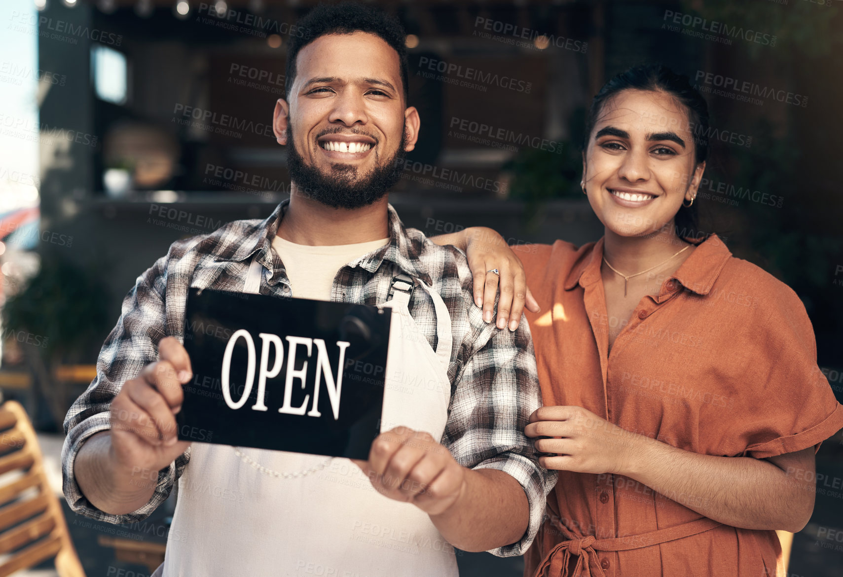 Buy stock photo Shot of two young restaurant owners standing outside together and holding an open sign