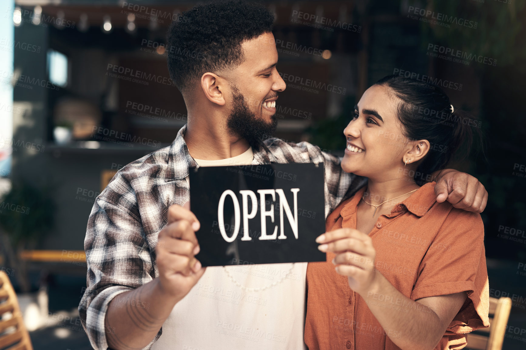 Buy stock photo Shot of two young restaurant owners standing outside together and holding an open sign