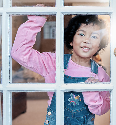 Buy stock photo Shot of an adorable little girl looking through the window at home
