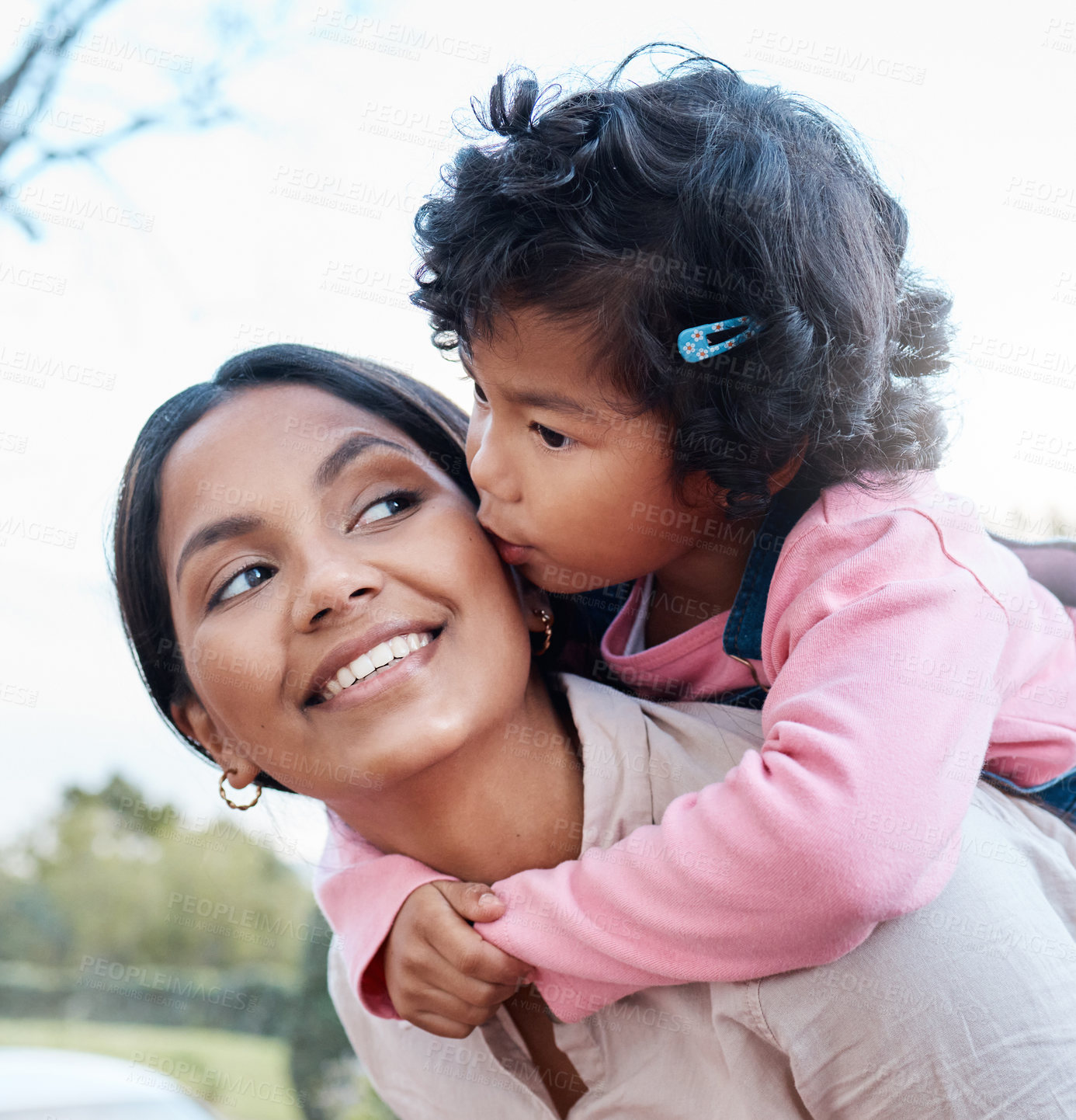 Buy stock photo Shot of a woman carrying her daughter on her back while standing outside