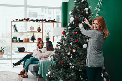 Buy stock photo Portrait of an attractive woman decorating a Christmas tree at home