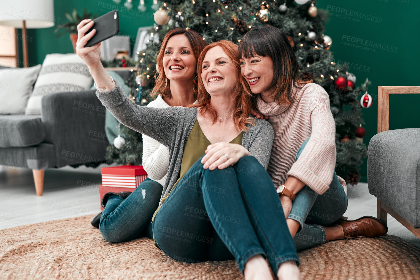Buy stock photo Shot of three attractive women taking Christmas selfies together at home