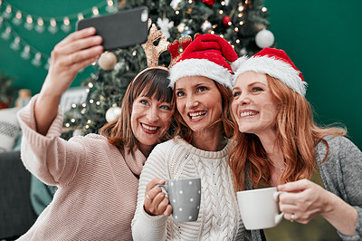 Buy stock photo Shot of three attractive women taking Christmas selfies together at home