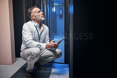 Buy stock photo Shot of a mature man using a digital tablet while working in a server room