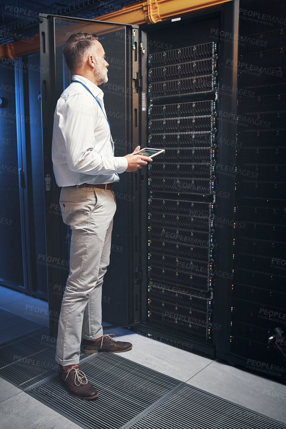 Buy stock photo Shot of a mature man using a digital tablet while working in a server room