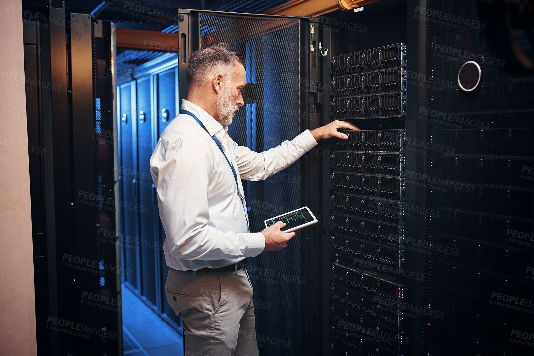 Buy stock photo Shot of a mature man using a digital tablet while working in a server room
