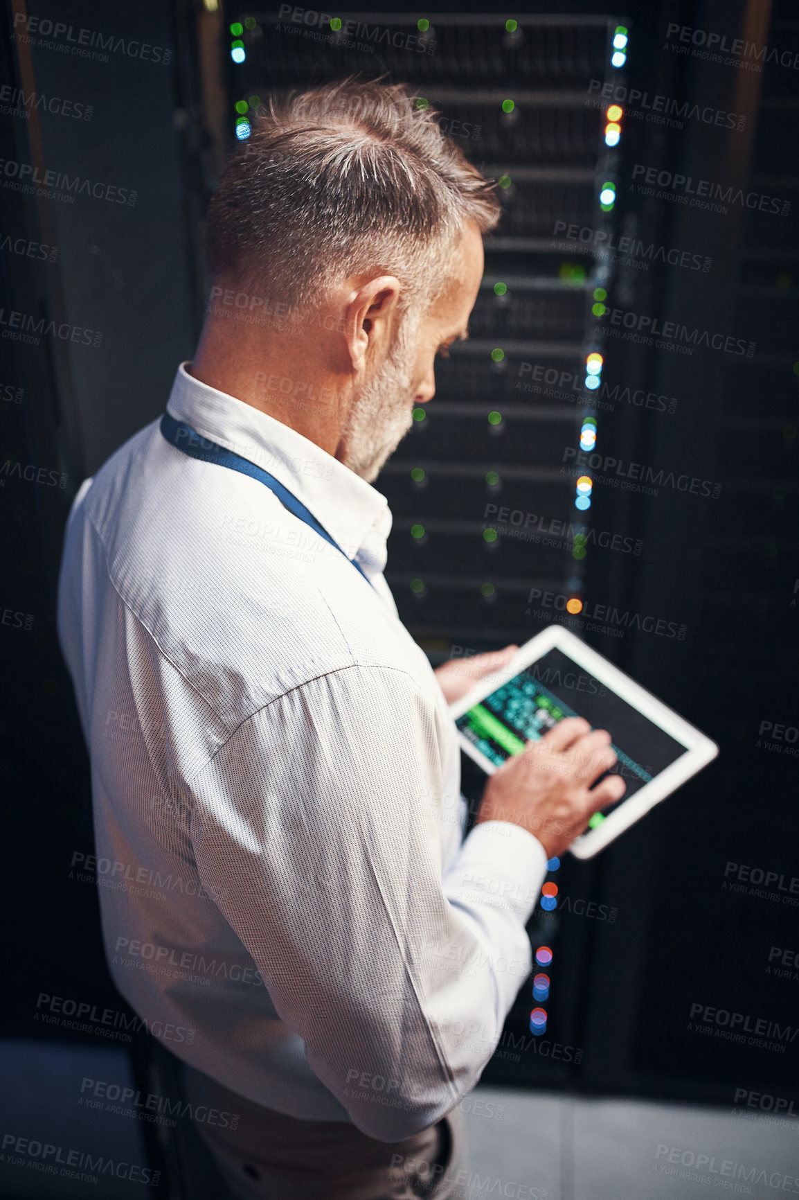 Buy stock photo Shot of a mature man using a digital tablet while working in a server room