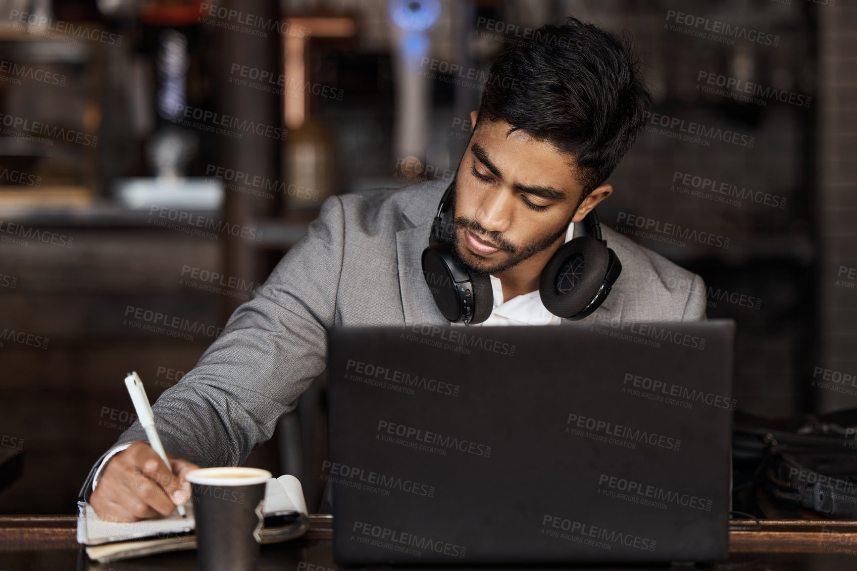 Buy stock photo Young business man, writing and cafe with notebook, laptop or plan for schedule, report and analysis. Indian businessman, book and pen for ideas, brainstorming or web design with focus in coffee shop