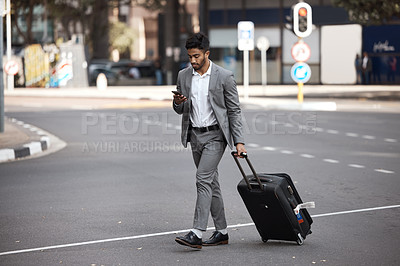 Buy stock photo Phone, travel and luggage with a business man walking in the city for an international trip. Mobile, communication and suitcase with a young male employee typing a text message on a street commute