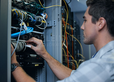 Buy stock photo Cropped shot of a handsome young male programmer working in a server room