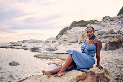 Buy stock photo Portrait, beach or black woman on rock to relax on holiday vacation or resting break in Greece at sunset. Tourist, girl or African person sitting at ocean, nature or sea for peace, wellness or travel